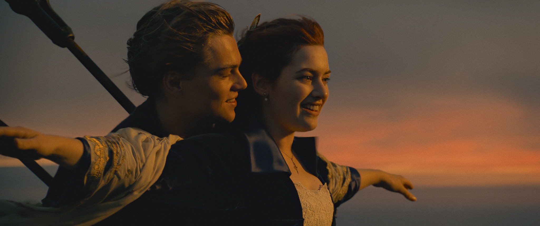 Jack (Leonard Dicaprio) and Rose (Kate Winslet) from Titanic embrace each other while looking out into the ocean as they stand together at the bow of the boat.